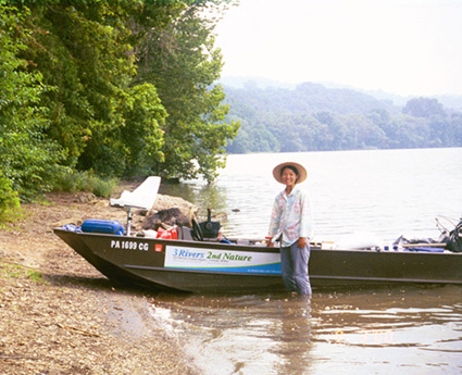 Reiko Goto by the 3r2n boat on the banks of the river